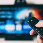 A remote control pointed at the tv with a streaming service on it. Photo courtesy of Glen Carstens-Peters on Unsplash.