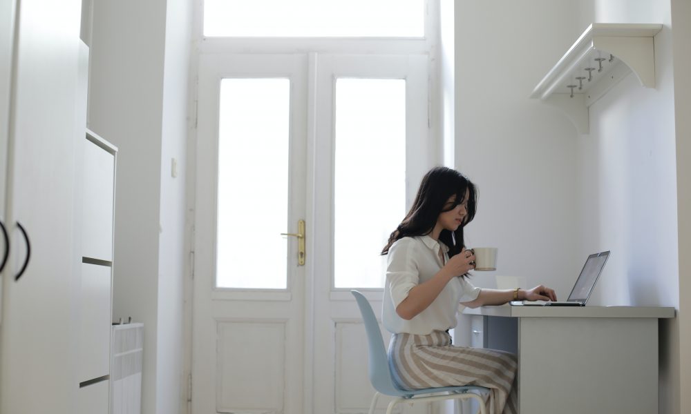 Woman sitting at a desk using her laptop. Photo courtesy of Jessica Ticozzelli on Pexels.