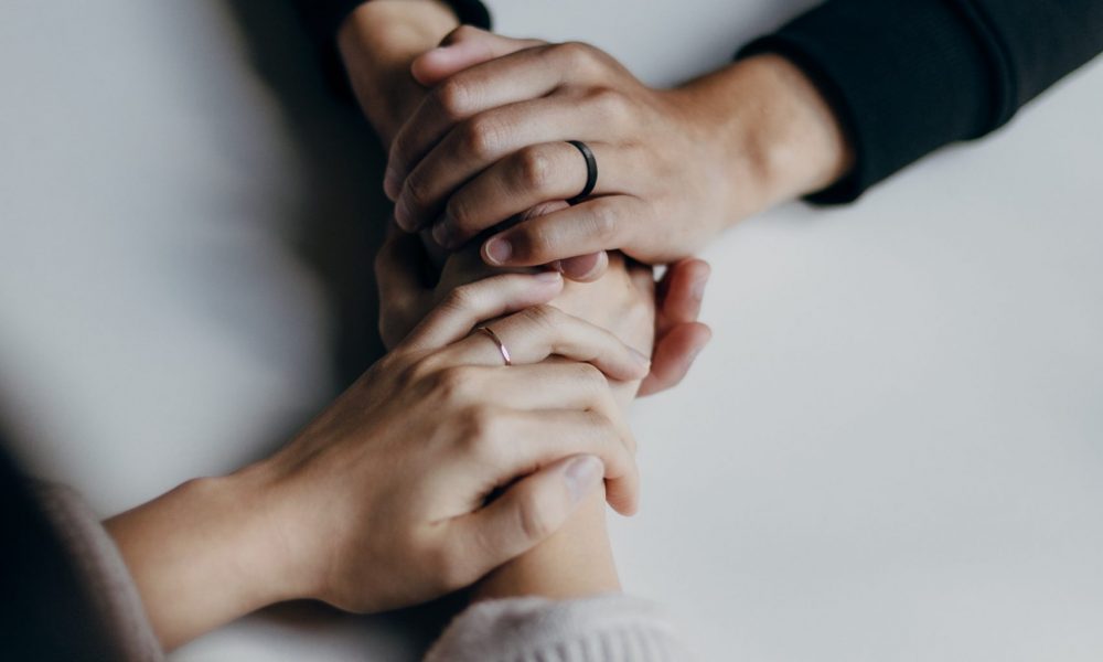 Photo of two people holding hands across a table. Image courtesy of Priscilla Du Preez.