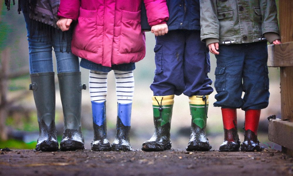 Image of four childrens cropped to show rain boots covered in mud