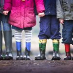 Image of four childrens cropped to show rain boots covered in mud