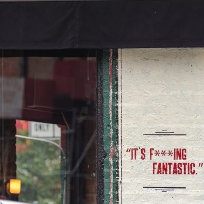 Writing on a cement wall that reads "it's f***ing fantastic"