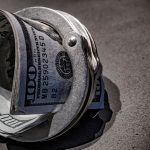 A pair of handcuffs with a hundred dollar bills inside