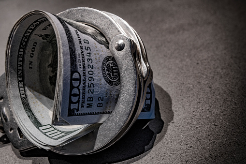 A pair of handcuffs with a hundred dollar bills inside