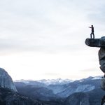 Man standing on a cliff pointing. Photo courtesy of Jeremy Perkins on Unsplash.