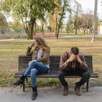 Woman And Man Sitting on Brown Wooden Bench by Vera Arsic