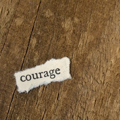 Ripped paper that has the word courage on it. Photo courtesy of Michael Dziedzic on Unsplash.