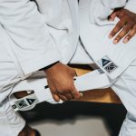 Photo of a man holding a white martial arts belt. Photo courtesy of Nathan Dumlao on Unsplash.