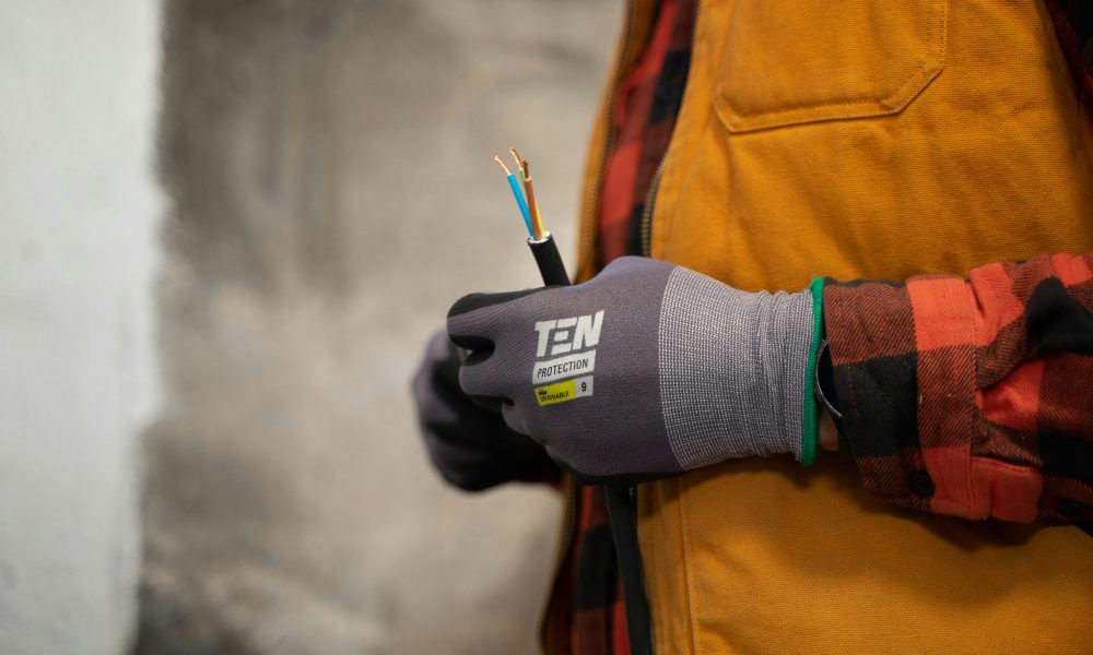 An electrician with work gloves holding a wire. Photo courtesy of Jimmy Nilsson Masth on Unsplash.