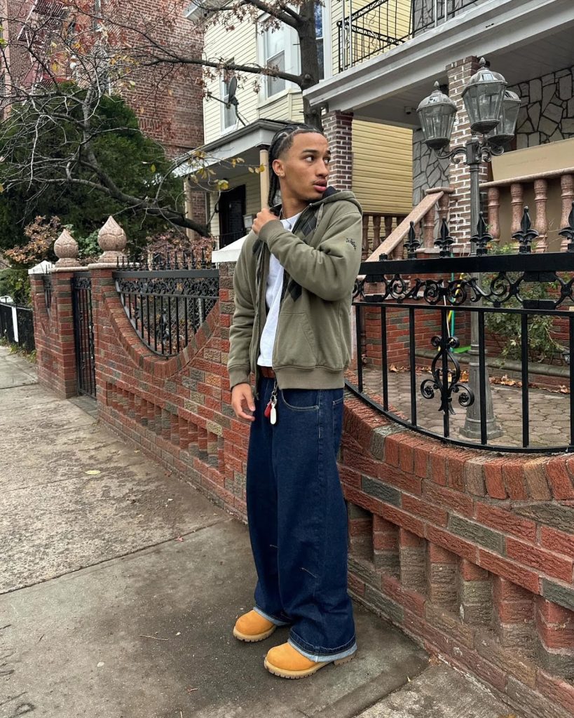 Instagram fashion post of a Black man waring a pea green zip-up sweatshirt, baggie dark blue jeans, and Timberlands