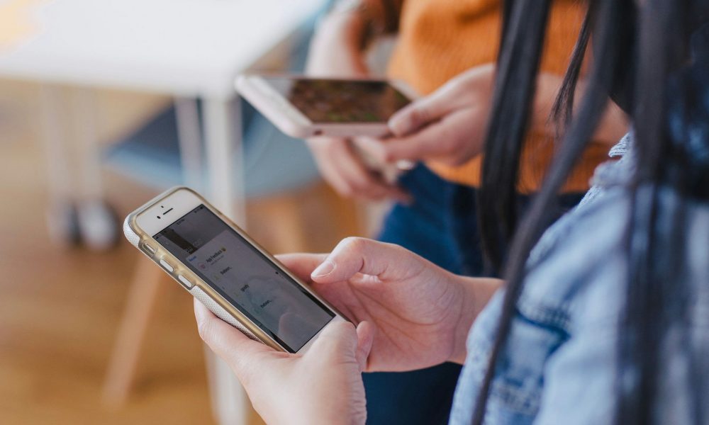 Photo of two people on their phone courtesy of Jason Goodman on Unsplash.
