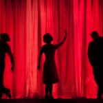 Photo of three actors behind a stage curtain courtesy of Kyle Head on Unsplash.