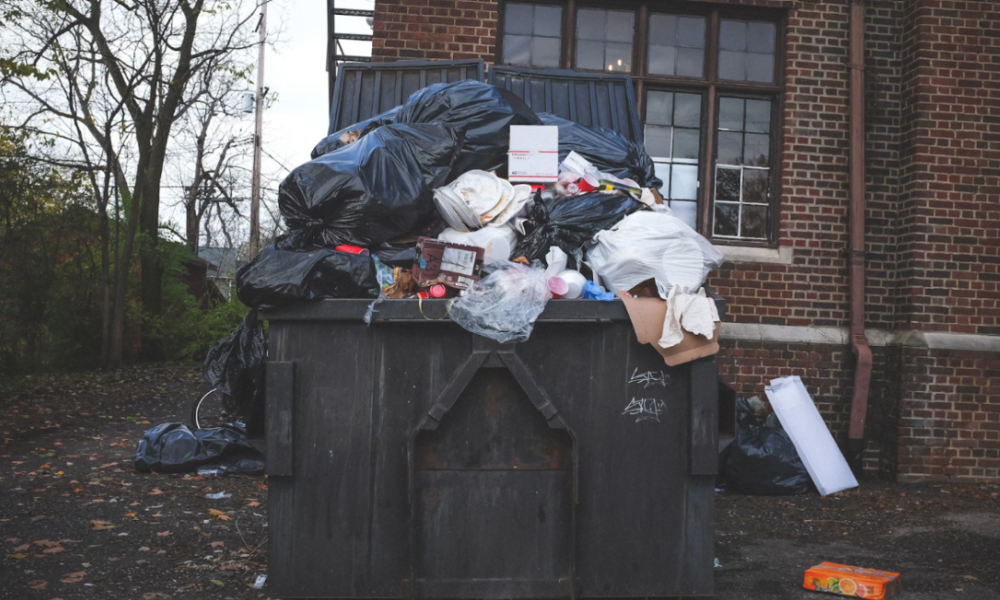 Overflowing dumpster outside of a house.