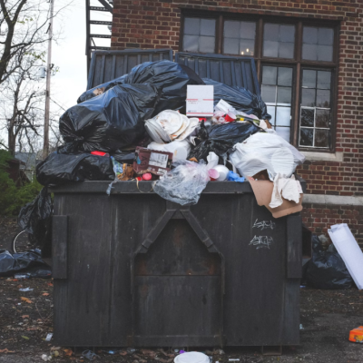 Overflowing dumpster outside of a house.