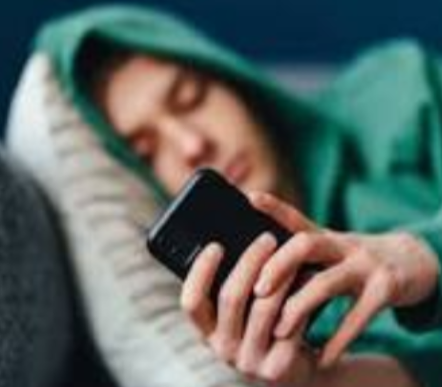 Photo of a teen in a hoodie using his phone.