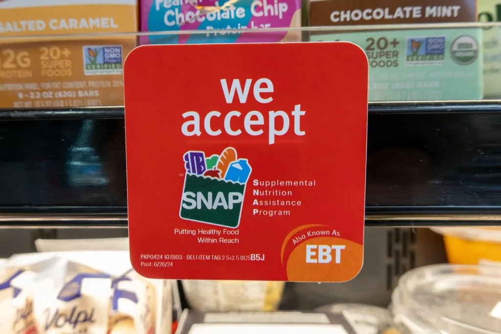 Sign that reads 'we accept SNAP' on a grocery store freezer door.