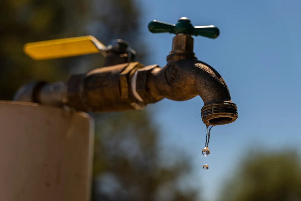 Close up of an outdoor water faucet with a few drops of water spilling out.