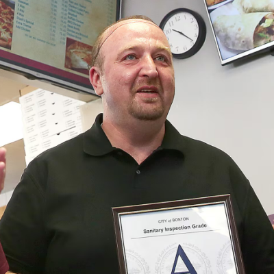 Stash's Pizza former owner holding his A inspection sign.