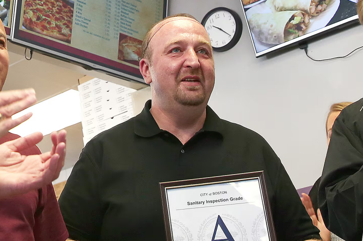 Stash's Pizza former owner holding his A inspection sign.
