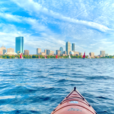 Red kayak on the Charles River, Boston skyline