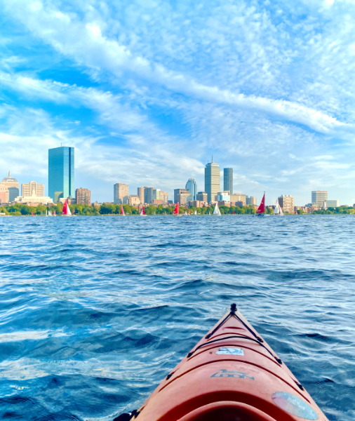 Red kayak on the Charles River, Boston skyline