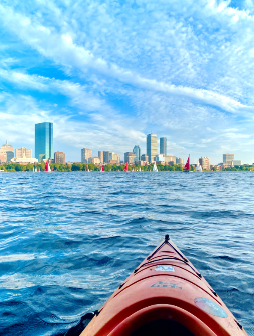 Red kayak on the Charles River, Boston skyline