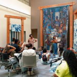 Students seated for a presentation on woven artworks.