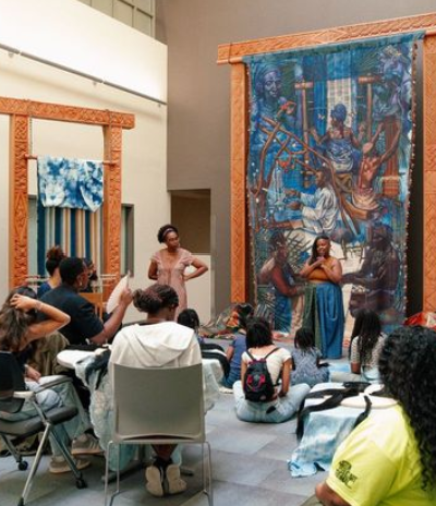 Students seated for a presentation on woven artworks.