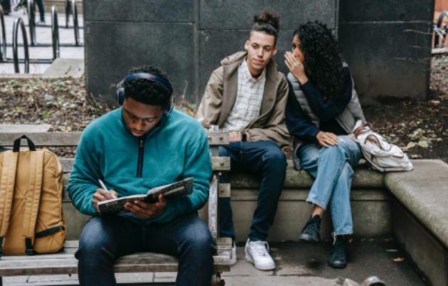 Two students whispering behind another student's back