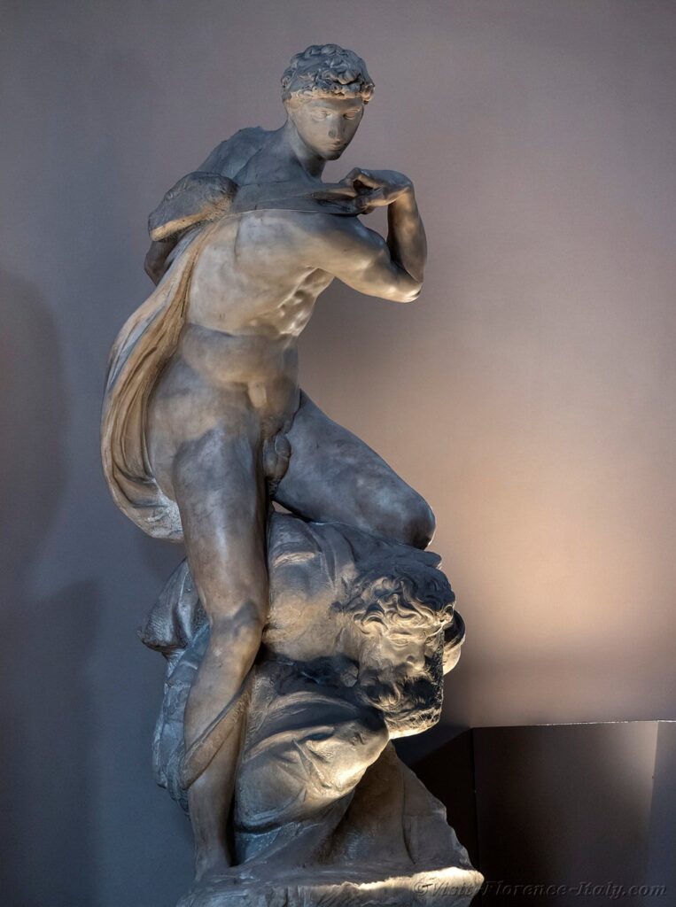 Michelangelo's "The Genius of Victory," a white marble statue of a nude muscular young man standing over a hunched bearded man.